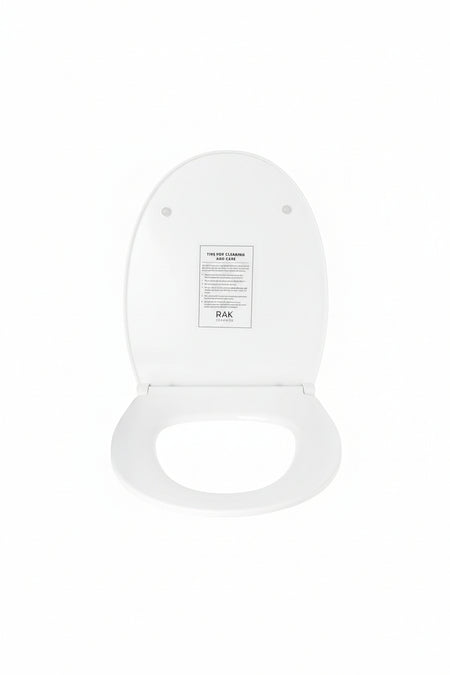 A white toilet seat lid shown open against a white background, with a small instruction card labeled RAK 