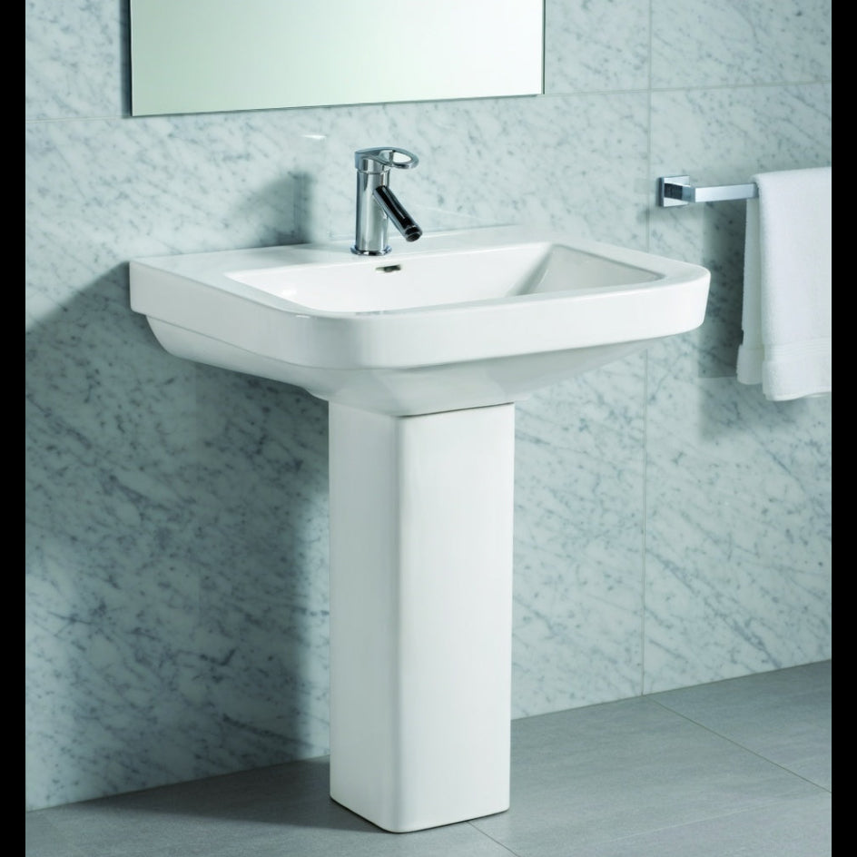 Bathroom sink with a mirror and towel on a tiled wall.