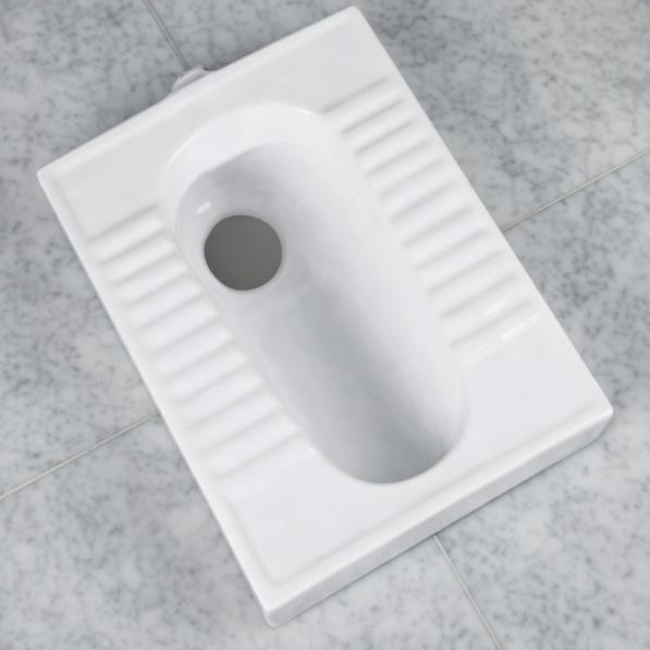 White squat toilet on a gray tiled floor